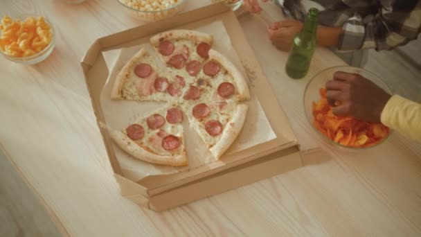 Widok z góry nierozpoznawalnych przyjaciół biorących przekąski i pizzę ze stołu, delektujących się obiadem w domu, śledzących strzał — Wideo stockowe