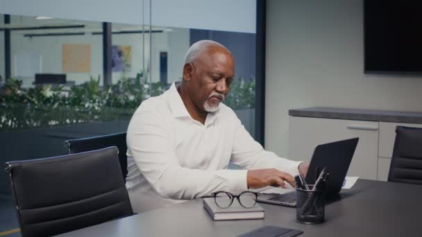 Ώριμος Αφροαμερικανός επιχειρηματίας που εργάζεται με το lap-top στο γραφείο, πληκτρολογώντας στο πληκτρολόγιο — Αρχείο Βίντεο