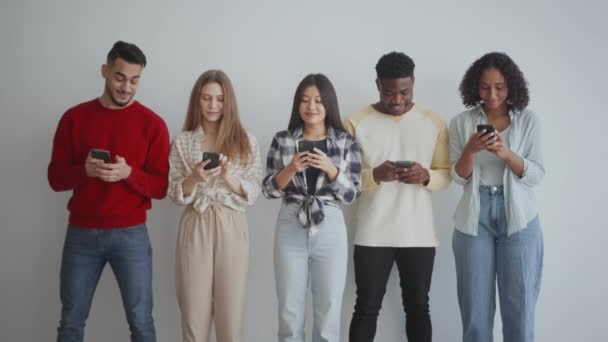 Grupo de jóvenes amigos alegres y diversos navegando por la web en teléfonos inteligentes, viendo las redes sociales y compartiendo noticias — Vídeo de stock