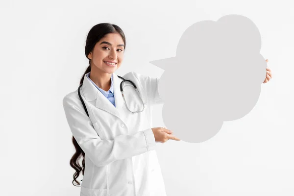 Vrolijke jonge indiaanse vrouwelijke arts in jas houden abstracte wolk met lege ruimte voor woorden — Stockfoto