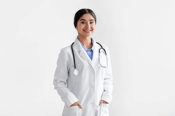 Retrato de doctora india milenaria sonriente confiada en bata blanca con estetoscopio —  Fotos de Stock