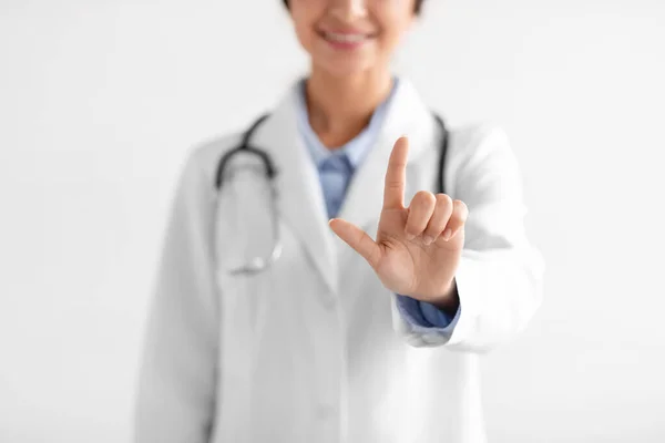 Recortado sonriente milenial india médico femenino en abrigo mostrando el dedo hacia arriba, gesto de la mano —  Fotos de Stock