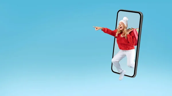 Aufgeregte blonde Frau mit Einkaufstüten springt aus Handy — Stockfoto