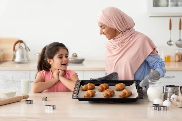 Heyecanlı küçük kız elinde bir tepsi taze kruvasanla Müslüman annesine bakıyor. — Stok fotoğraf