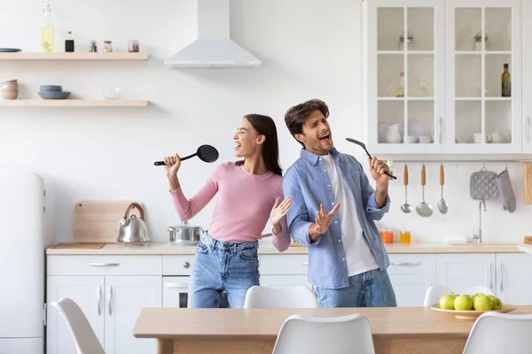 Dertsiz, neşeli, duygusal genç çift beyaz mutfakta şarkı söyleyip dans ediyor. — Stok fotoğraf