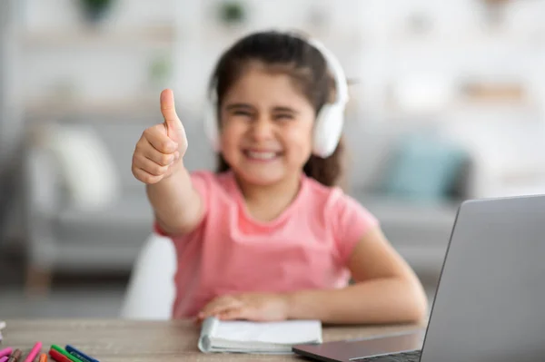 Ótima escolha. Menina bonito em fones de ouvido mostrando polegar para cima na câmera — Fotografia de Stock