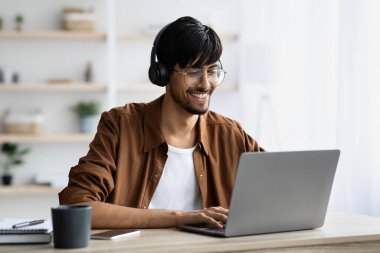 Webinar 'a katılan gülümseyen Hintli adam, dizüstü bilgisayarda klavye kullanıyor.