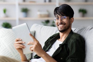 Evde dijital tablet kullanan rahat Hintli adam.