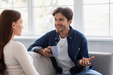 Gülümseyen beyaz bir erkek ve kadın kahve içip sohbet ediyor ve hafta sonunu birlikte geçiriyorlar.