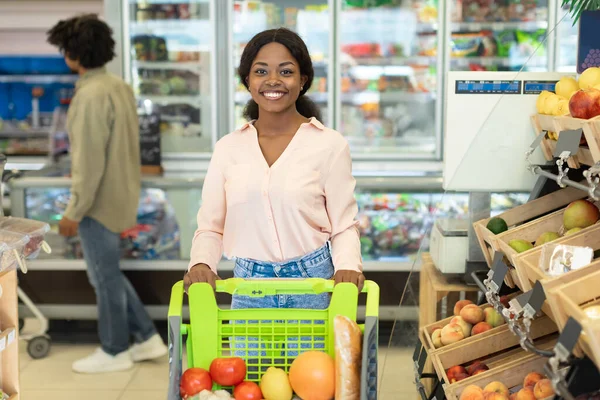 Svart kvinna Shopping livsmedel dosera med butik vagn i snabbköpet — Stockfoto