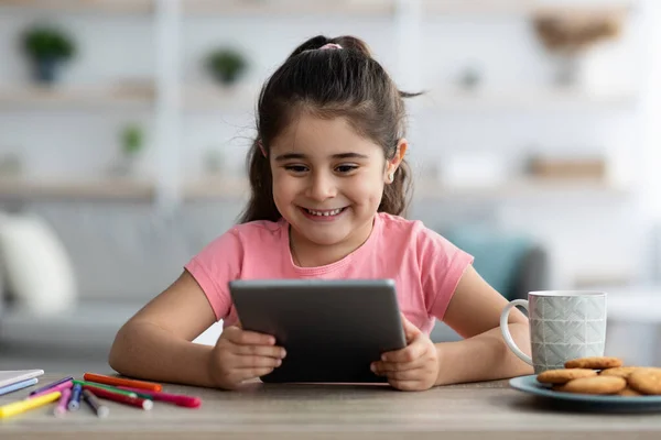 Gadgets para crianças. Menina feliz relaxando com tablet digital em casa — Fotografia de Stock