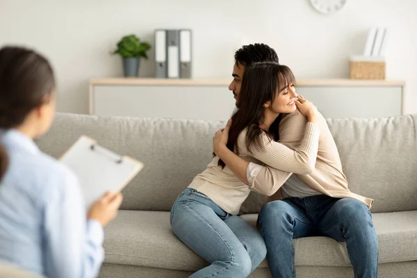 Sevgili Arap çift başarılı bir evlilik terapisinden sonra danışman odasında sarılıyor, profesyonel psikologa minnettarlar. — Stok fotoğraf