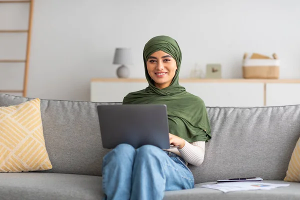 Evde dizüstü bilgisayarında aile ya da arkadaşıyla çevrimiçi görüşme yapan tesettürlü genç bir Arap kadın var. — Stok fotoğraf