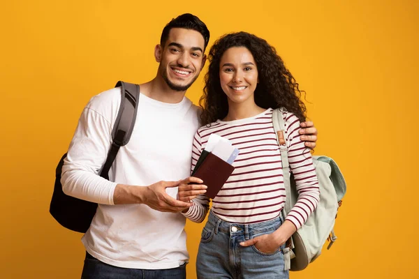 Viajeros felices. Pareja árabe sonriente con mochilas, pasaportes y boletos de viaje — Foto de Stock