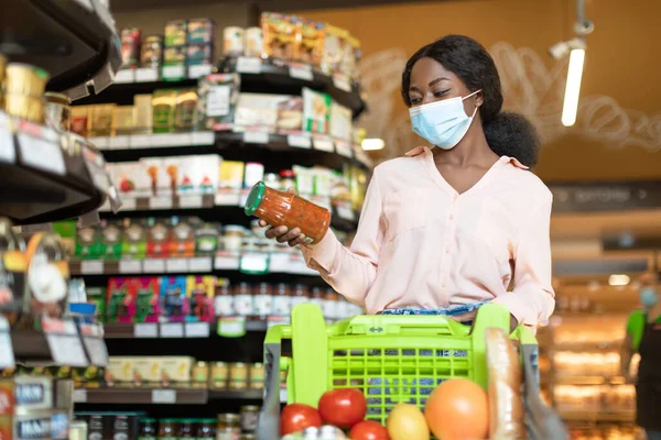 Αφρικανική γυναίκα ψώνια φορώντας μάσκα προσώπου Holding Jar στο σούπερ μάρκετ — Φωτογραφία Αρχείου
