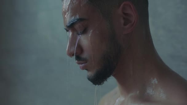 Κατάθλιψη. Κοντινό πορτρέτο του νεαρού στρεσαρισμένου δυστυχισμένου Άραβα που στέκεται στο ντους, αργή κίνηση — Αρχείο Βίντεο