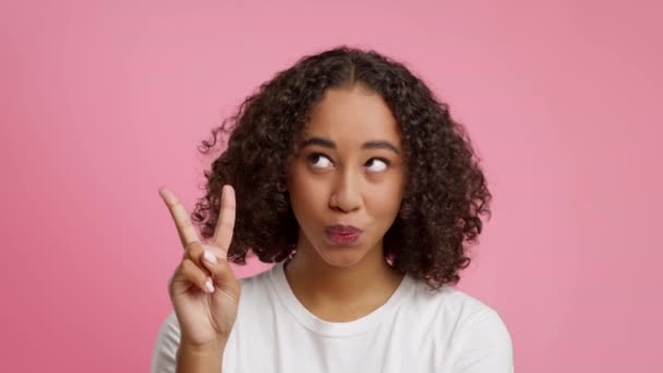 Vrolijke zwarte dame Gesturing V-teken poseren met plezier, roze achtergrond — Stockvideo