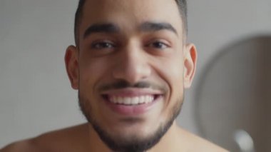 Mevsimsel cilt nemlendirici. Yanaklarına asker boyası sürmüş gibi krem süren genç, oyuncu Arap 'ın portresi.