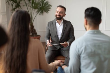 Genç çift terapi seansında erkek terapistle oturuyor.