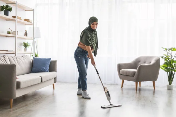 Mujer musulmana limpieza piso con aerosol fregona en salón eoom —  Fotos de Stock