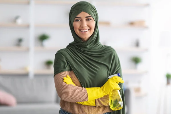 Весела молода ісламська домогосподарка тримає пляшку спрею для прибирання — стокове фото