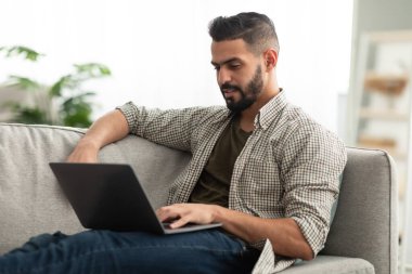 Bin yıllık Arap erkek serbest çalışan ev ofisinin bilgisayarında çalışıyor.