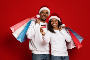 Neşeli Afrikalı Amerikalı genç adam ve kadın Noel hediyeleri alıyorlar.