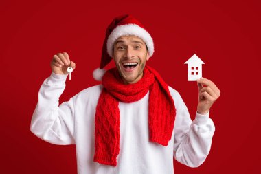 Noel Baba Şapkalı Neşeli Adam Ev Anahtarları ve Kağıt Ev Simgesi Tutuyor