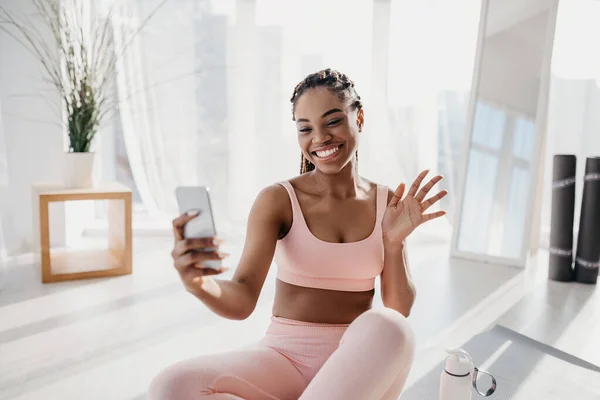 Fit schwarze Frau Video-Chat auf dem Smartphone während des Heimtrainings, sprechen mit Personal Trainer online, winken der Webcam — Stockfoto