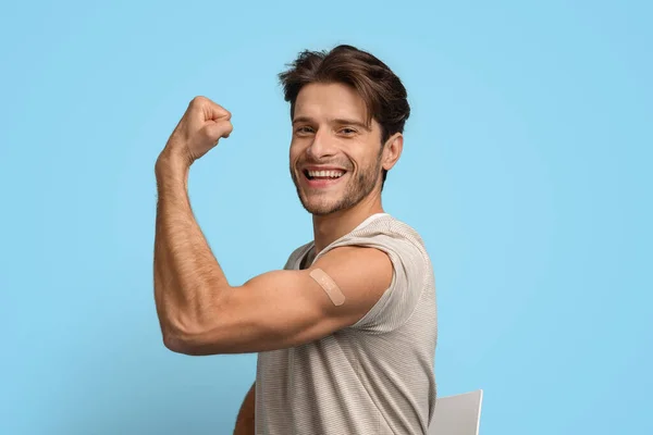 Vaccinerad ung man som demonstrerar biceps med självhäftande band efter injektion — Stockfoto