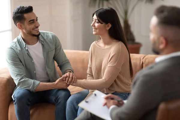 Lykkelig par som snakker i terapi med mannlig terapeut – stockfoto