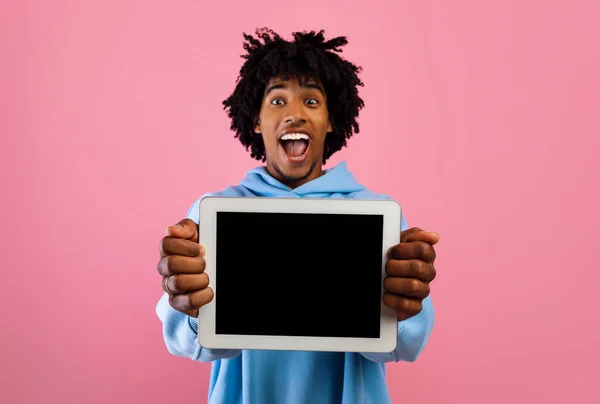 Adolescente negro lleno de alegría mostrando tableta digital con maqueta para el diseño del sitio web o aplicación sobre fondo rosa —  Fotos de Stock