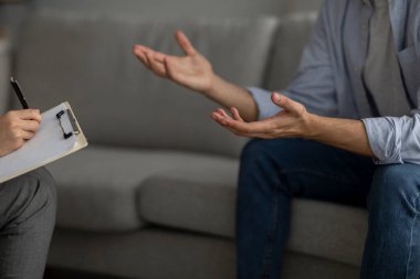 Tanımlanamayan bir adam psikoterapistle konuşuyor, koltukta oturuyor ve danışmanla görüşüyor.