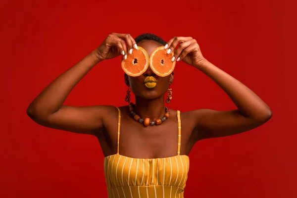 Zabawna czarna pani trzymająca pomarańczowe kółka nad oczami — Zdjęcie stockowe