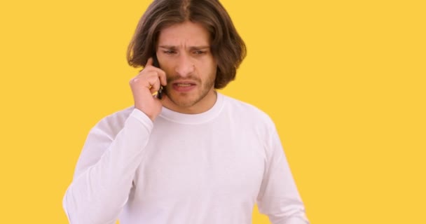 Мобильная ссора. Студийный портрет молодого недовольного парня, разговаривающего негативно, спорящего с собеседником по мобильному телефону — стоковое видео