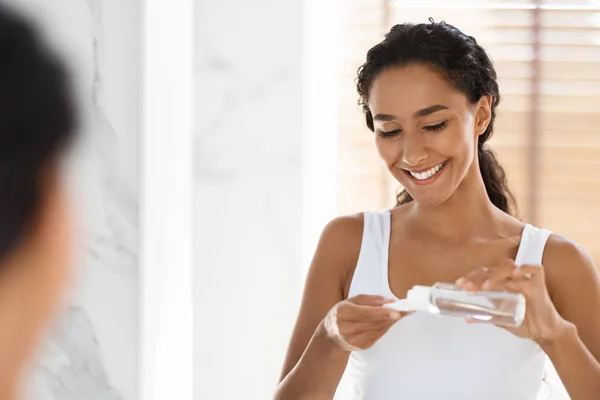 Limpeza de Caras. Jovem senhora derramando água micelar em almofada de algodão no banheiro — Fotografia de Stock
