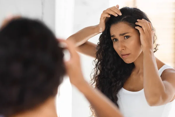 Problem z łupieżem. Zdenerwowana młoda kobieta patrząc na korzenie włosów w łazience — Zdjęcie stockowe