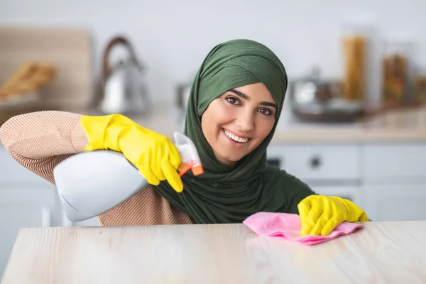 Cheerful young muslim woman cleaning dining table at kitchen — Stock Photo, Image