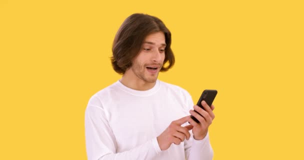 Концепція онлайн-спілкування. Молодий безтурботний чоловік веб-серфінг на мобільному телефоні, читання позитивних новин і кишенькова голова — стокове відео