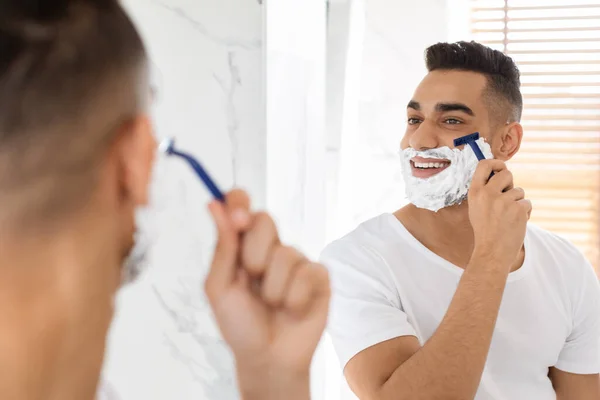 Porträt von hübsch jung arabisch mann rasieren in der nähe spiegel im badezimmer — Stockfoto