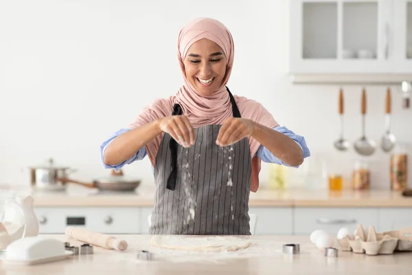 Islamica signora in hijab cuocere in cucina, spruzzare farina su laminato pasta — Foto Stock