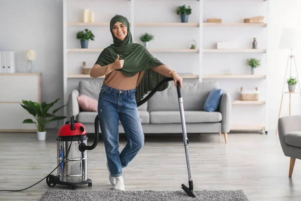 Donna musulmana pulizia tappeto con aspirapolvere, mostrando pollici verso l'alto — Foto Stock