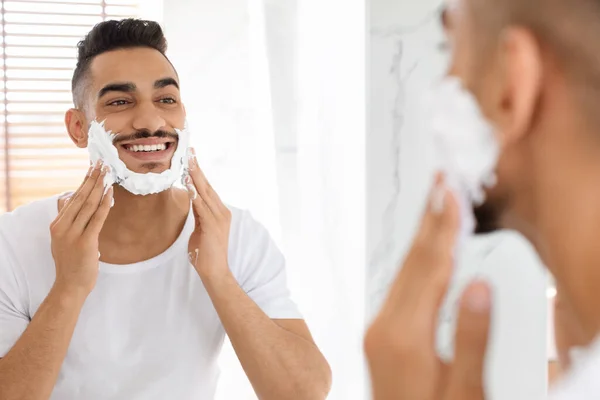 Schön Arab Mann Applying Rasierschaum Auf Gesicht Near Mirror In Badezimmer — Stockfoto