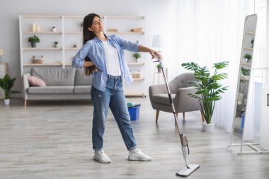 Temizlik sırasında sırt ağrısı çeken yorgun bir kadın.