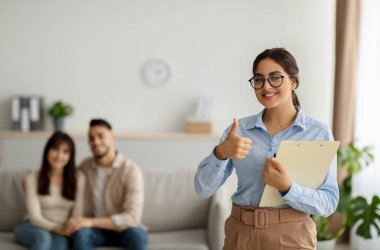 Başarılı bir terapi. Mutlu Arap psikoloğu, ofiste sevgili bir çiftle yaptığı seans sırasında el hareketi gösteriyor.