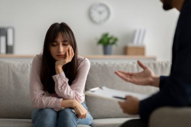 Depresyondan muzdarip mutsuz genç Arap bayan, psikolog tavsiyeleri, doktorların ofisinde oturmak, yer kopyalamak