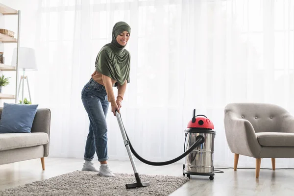 Allegro donna musulmana pulizia tappeto con aspirapolvere — Foto Stock