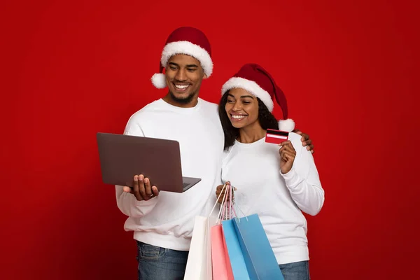 Glada par med shoppingväskor, laptop och kreditkort — Stockfoto