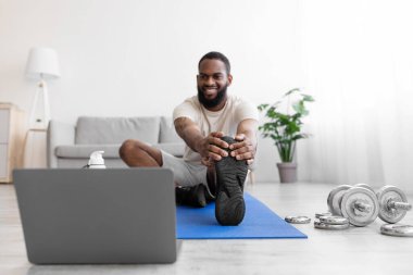 İyi ki genç siyah sakallı erkek atlet halterlerle yerde bacak esnetiyor.