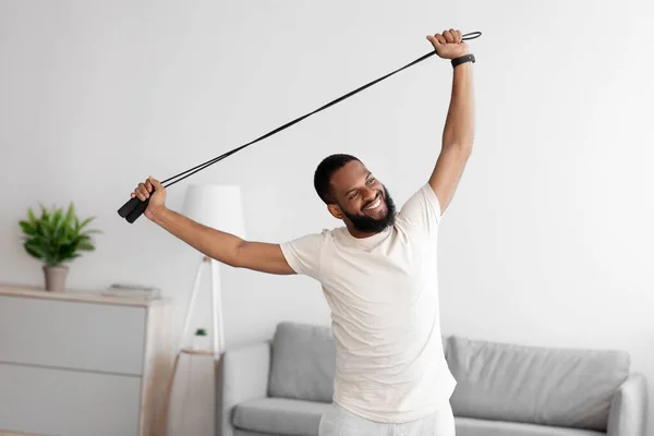 Ευτυχής χαρούμενη χιλιετή αφροαμερικανός γενειοφόρος τύπος κάνει ασκήσεις με σχοινάκι στο σαλόνι — Φωτογραφία Αρχείου